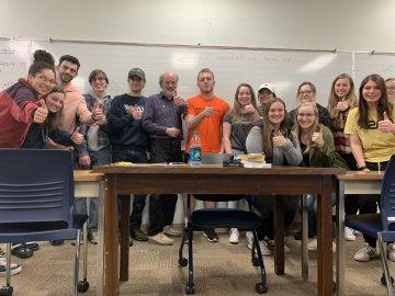 Students from the Honors Program stand in front of a desk.