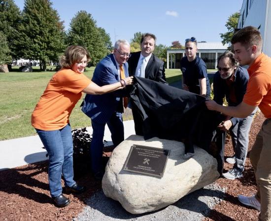 A plaque dedicating the campus pergola in honor of JP Ramel is unveiled.